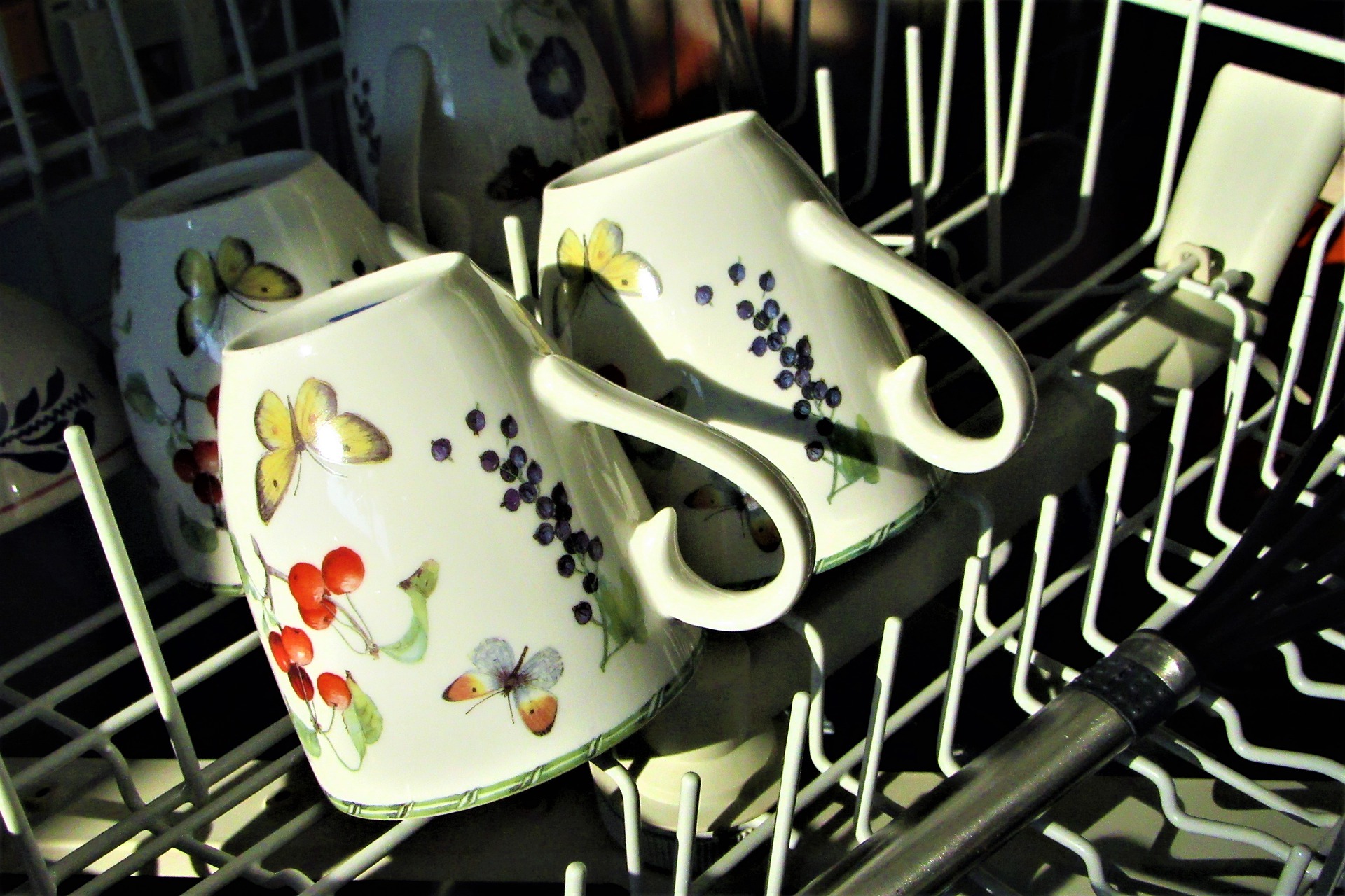 The top rack of a dishwasher with tea cups in it, which is why you need to know how to clean a dishwasher.