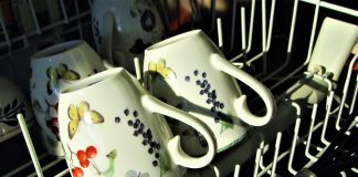 The top rack of a dishwasher with tea cups in it, which is why you need to know how to clean a dishwasher.