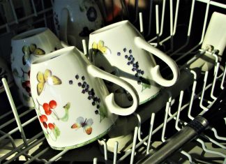 The top rack of a dishwasher with tea cups in it, which is why you need to know how to clean a dishwasher.